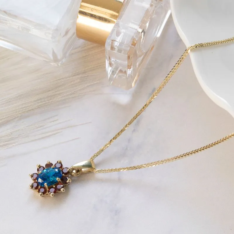 Lucia pendant yellow gold with garnet stones and blue zircon in the middle