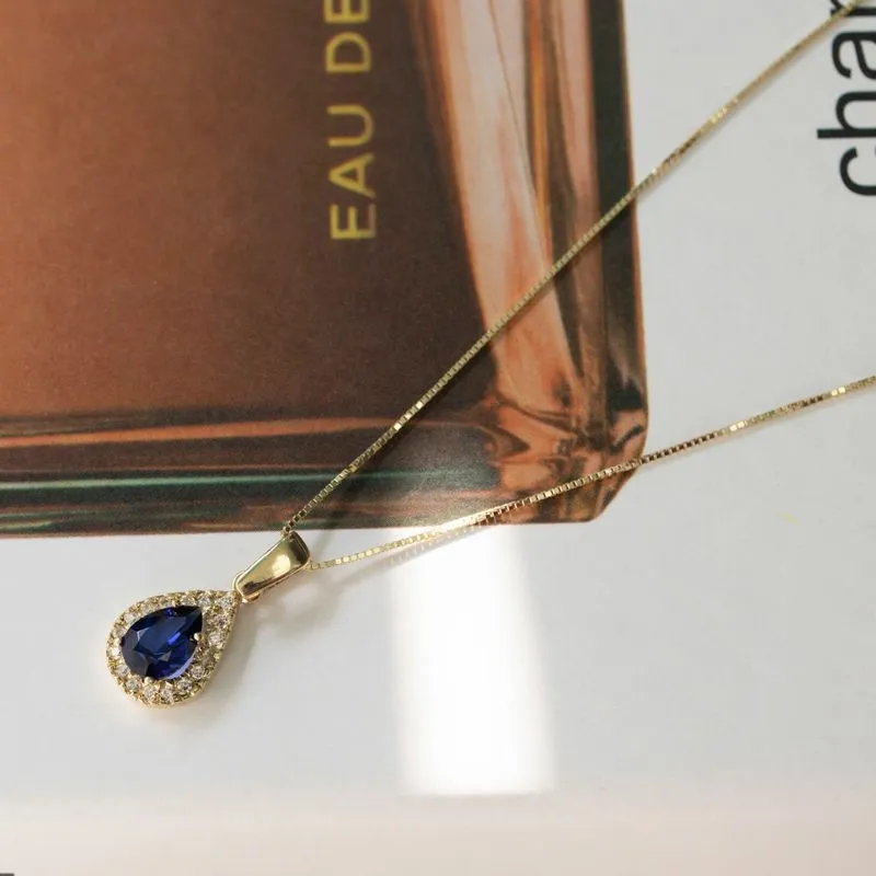 Yellow gold drop necklace with white zircons and a blue zircon in the center